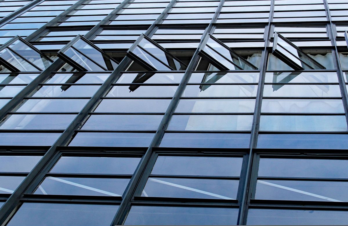 Looking up a glass curtain wall with dark aluminium mullions