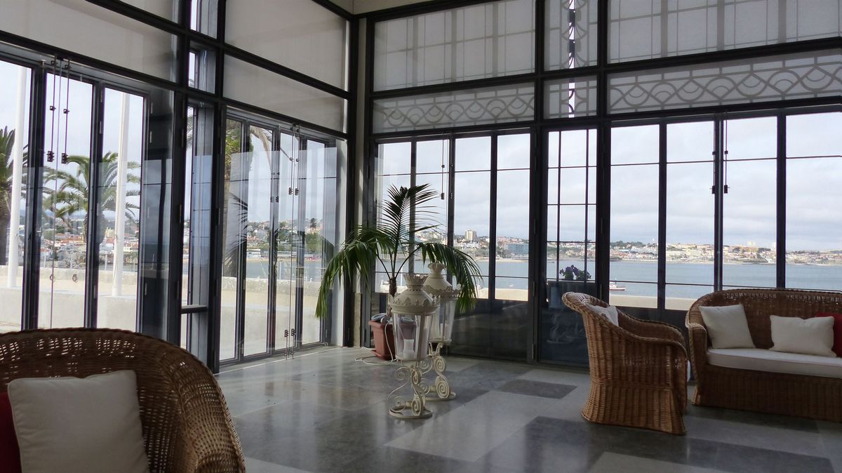 Black-framed glass room with sliding panels and the sea beyond