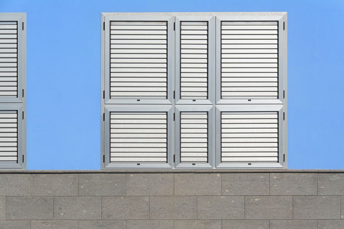Louvre shutters on a building facade against a blue sky