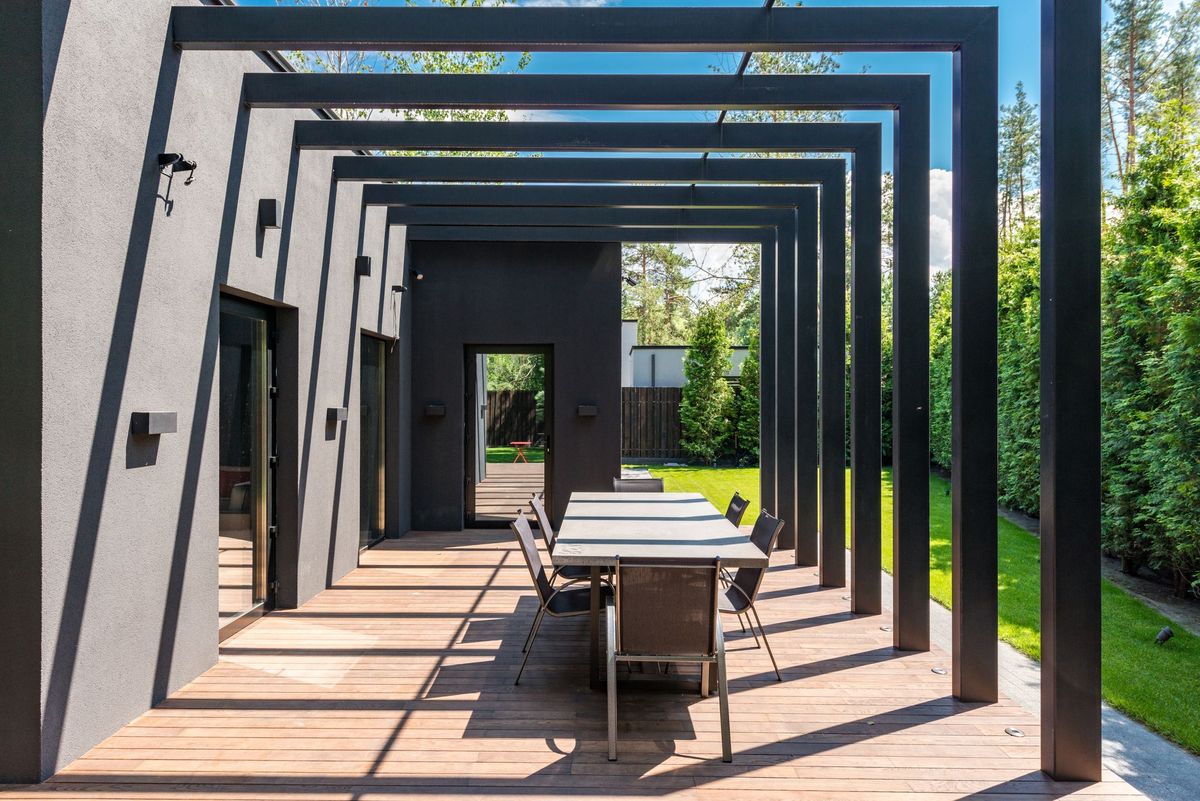 Black aluminium pergola over an outdoor dining deck