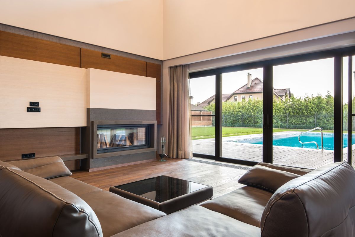 Large black-framed aluminium sliding doors opening from a lounge onto a pool
