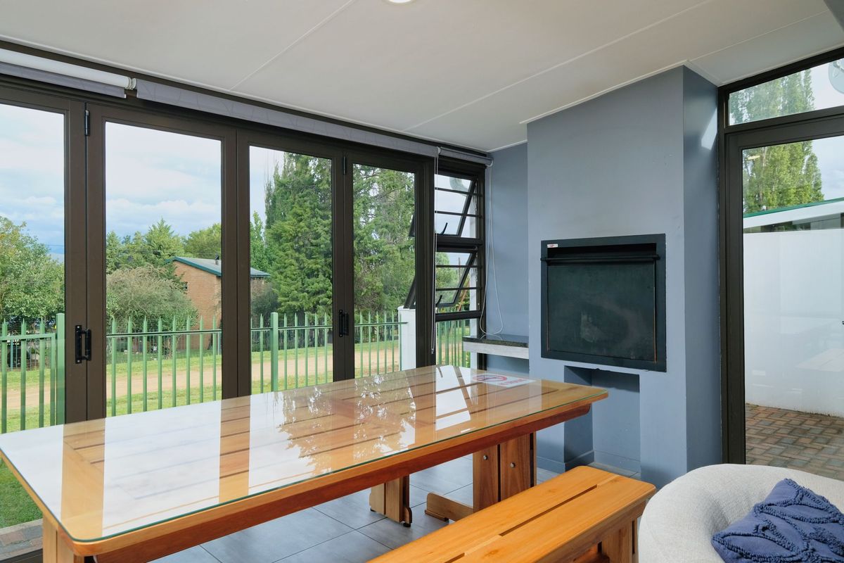 Stacking glass doors wrapping an entertainment room with a braai and a long table
