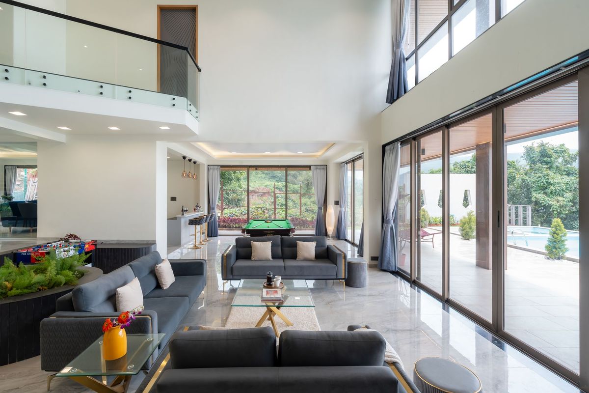 Double-volume living room with full-height dark-framed sliding doors along one wall