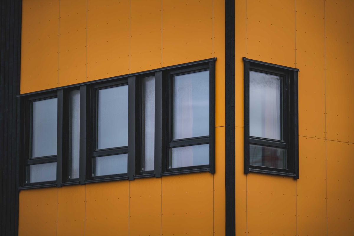 Runs of black-framed windows on an orange-clad facade, with a corner window